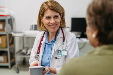 Önleyici sağlık muayenesi sırasında tansiyonunu ölçtüren yaşlı bir kadın.