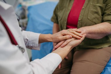 Bakıcı doktor hasta elini tutuyor, şefkatli bir jest yapıyor..