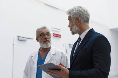 Doktor hastane müdürüyle konuşuyor, ona belgeleri gösteriyor..