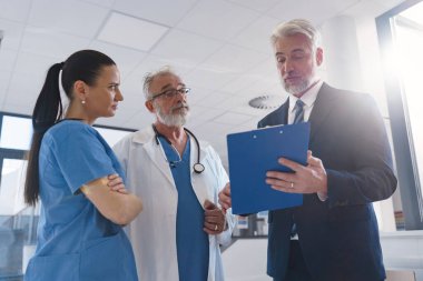 Tıbbi satış temsilcisi doktorlara yeni ilaçlar sunuyor. Hastane koridorunda ayakta duruyor. Hastane ayarları.