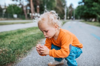 Meraklı çocuk dışarıda küçük bir çiçeği inceliyor. Doğayı keşfetmek