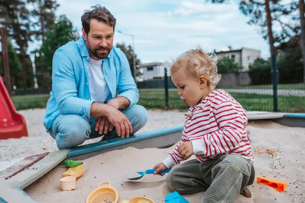 Baba ve küçük çocuk oyun parkında oynuyorlar, hafta sonu eğlencesi..