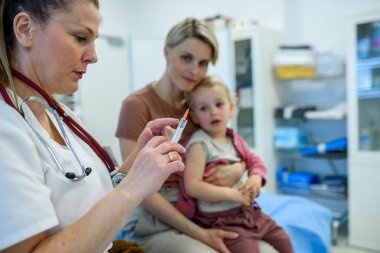 Bebek, pediatrik muayene sırasında aşı oluyor. Koruyucu bakım.