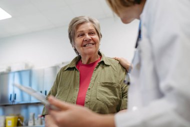 Geriatrist, muayene sırasında yaşlı bir hastayla test sonuçları hakkında konuşuyor. Tıbbi danışma.