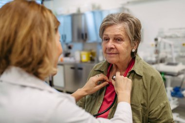 Geriatrist doktor steteskopla yaşlı hastayı muayene ediyor. Yaşlı kadınlar için rutin sağlık muayenesi.