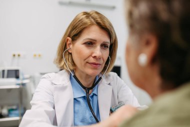 Geriatrist doktor steteskopla yaşlı hastayı muayene ediyor. Yaşlı kadınlar için rutin sağlık muayenesi.