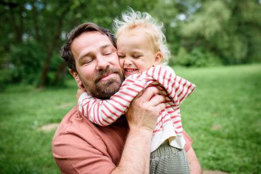 Babasının portresi. Küçük oğluna sarılıyor, birlikte eğleniyor. Babalar Günü konsepti.