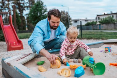 Baba ve küçük çocuk oyun parkında oynuyorlar, hafta sonu eğlencesi..