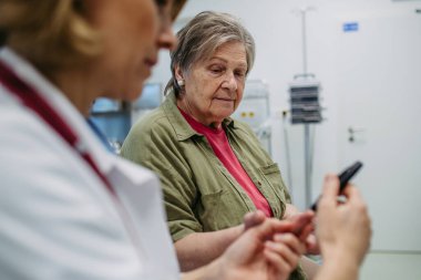 Kadın doktor muayenede kan şekeri ölçer kullanıyor. Diyabet testi.