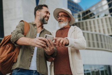 Olgun oğul ve baba birlikte seyahat ediyor, akıllı telefondan haritaya bakıyor..