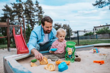 Baba ve küçük çocuk oyun parkında oynuyorlar, hafta sonu eğlencesi..