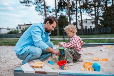 Baba ve küçük çocuk oyun parkında oynuyorlar, hafta sonu eğlencesi..