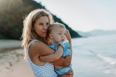 Güneşli sahil tatilinde, genç anne ve kız arasında hassas bir an..