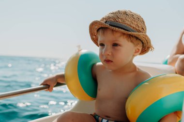 Yaz tatilinde teknede elinde korkulukla oturan küçük bir çocuk..