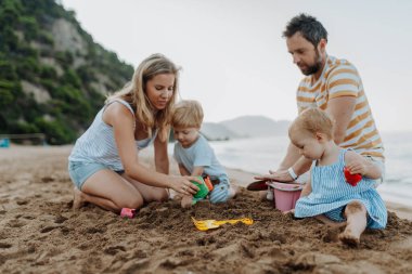 İki küçük çocuk yaz tatilinde kumsalda paretlerle oynuyorlar..
