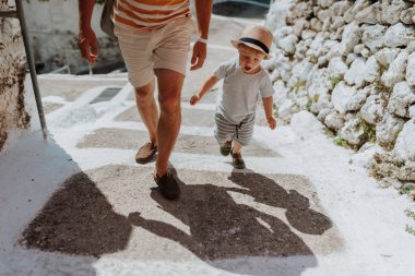 Yaz tatilinde kasabada yürüyen baba ve bebeğin bacaklarına yaklaş. Boşluğu kopyala.