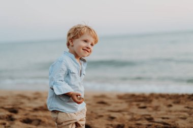 Yaz tatilde kumsalda ayakta, eğleniyor bir neşeli küçük yürümeye başlayan çocuk.