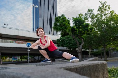 Şehirde spor yapan, dışarıda vücut ağırlığı egzersizi yapan bir kadın.