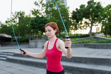 Şehirde ip atlayan genç bir kadın egzersiz yapıyor..