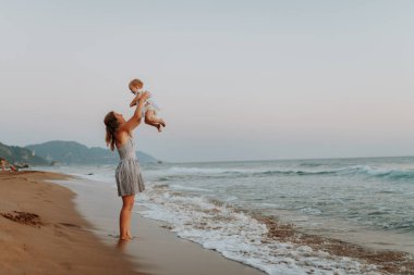 Annenin küçük kızıyla güneşli plajda oynadığı sahne, yaz tatili..