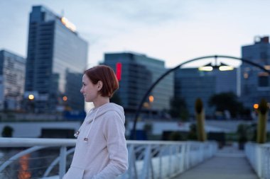 Sportif kadın koşucu sabah koşusuna hazırlanıyor, nehire bakıyor..