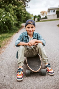 Şirin Çocuk sokakta uzun tahtasında oturuyor, tatilin tadını çıkarıyor..