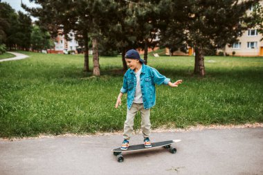 Genç çocuk sokakta uzun tahta sürmeyi öğreniyor..
