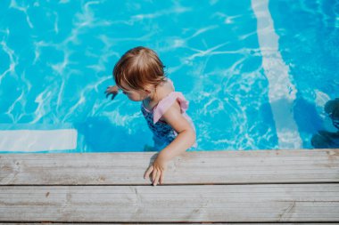 Havuzda sığ sularda oynayan küçük kız, yüksek açı manzaralı..