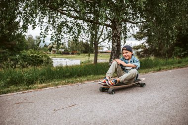 Şirin Çocuk sokakta uzun tahtasında oturuyor, tatilin tadını çıkarıyor..
