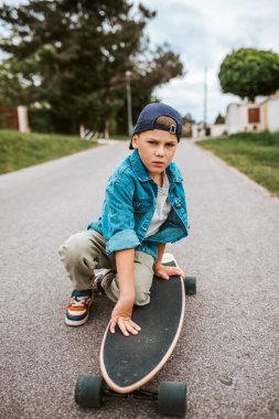 Şirin Çocuk sokakta uzun tahtasında oturuyor, tatilin tadını çıkarıyor..