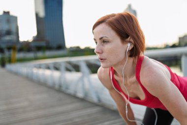 Dişi koşucu dinleniyor ve soluklanıyor. Sabah koşusundan sonra eğiliyor..