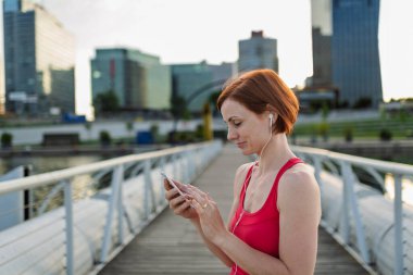 Kadın koşucu, sabah saatlerinde şehir köprüsünde koşarken akıllı telefondan müzik çalıyormuş..