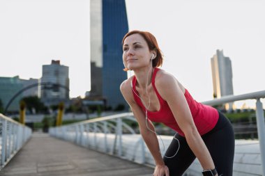 Dişi koşucu dinleniyor ve soluklanıyor. Sabah koşusundan sonra eğiliyor..