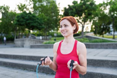 Şehirde ip atlayan genç bir kadın egzersiz yapıyor..