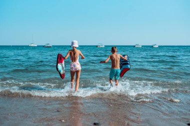 Bedenleri ve dikiz aynasıyla denize koşan çocuklar..
