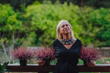 Terasta saksıda bekleyen olgun bir kadın. Hindistan yaz konsepti.