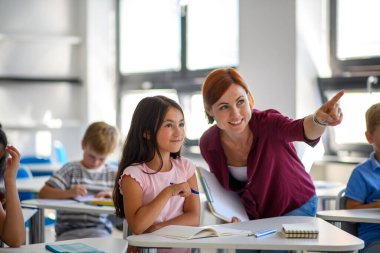 Öğretmen ilkokulda çocuklarla konuşuyor. Okula geri dön..