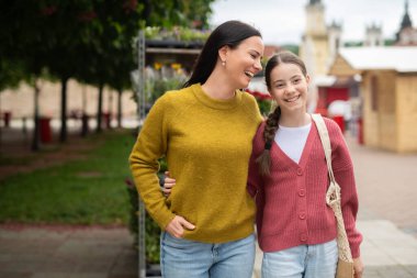 Anne kızını kucaklıyor sokakta yürürken, şefkatli bir ebeveyn gibi..