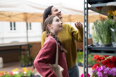 Anne ve kız pazardan çiçek seçiyor, bitki alıyorlar..