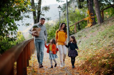 Kız kardeşler ve ebeveynler sıcak sonbahar gününde parkta yürürler. Hindistan yaz konsepti.