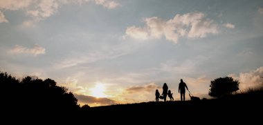 Günbatımında sonbahar doğasında iki küçük çocuklu aile silueti. Kopyalama alanı olan pankart.