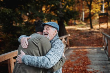 Dedem ve torunum sonbahar parkının ortasında sarılıyorlar. Sonbahar sezonu.
