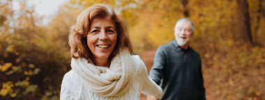 Kocasıyla ormanda yürüyüp el ele tutuşan son sınıf öğrencisi mutlu bir kadın. Kopyalama alanı olan pankart.