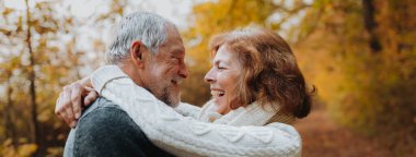 Yaşlı çifti kucaklamak, sonbahar sezonunda dışarıda vakit geçirmek, fotokopi alanı ile pankart..