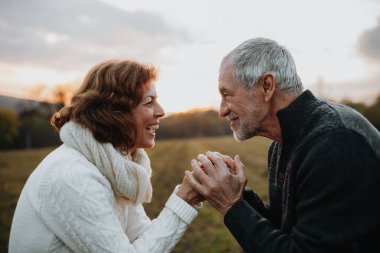Sonbahar günbatımında el ele tutuşan sevgi dolu yaşlı çift..