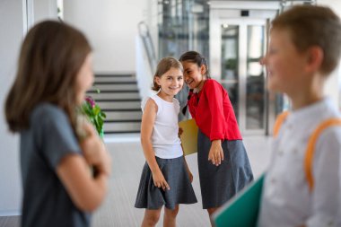 Okullu kızlar sınıf arkadaşlarıyla dalga geçiyor ya da dedikodu yapıyor, birlikte kıkırdıyor..