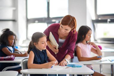 Öğretmen ilkokulda çocuklarla konuşuyor. Okula geri dön..