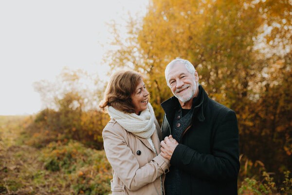 Пара пенсионеров, стоящая посреди цветущих осенних лесов. Осенний сезон.
