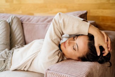 Rahat bir kadın dinleniyor, kanepede gözleri kapalı dinleniyor. Evde huzurlu bir an..