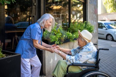 Yaşlı bakıcı ile tekerlekli sandalyedeki yaşlı kadın arasındaki hassas an..